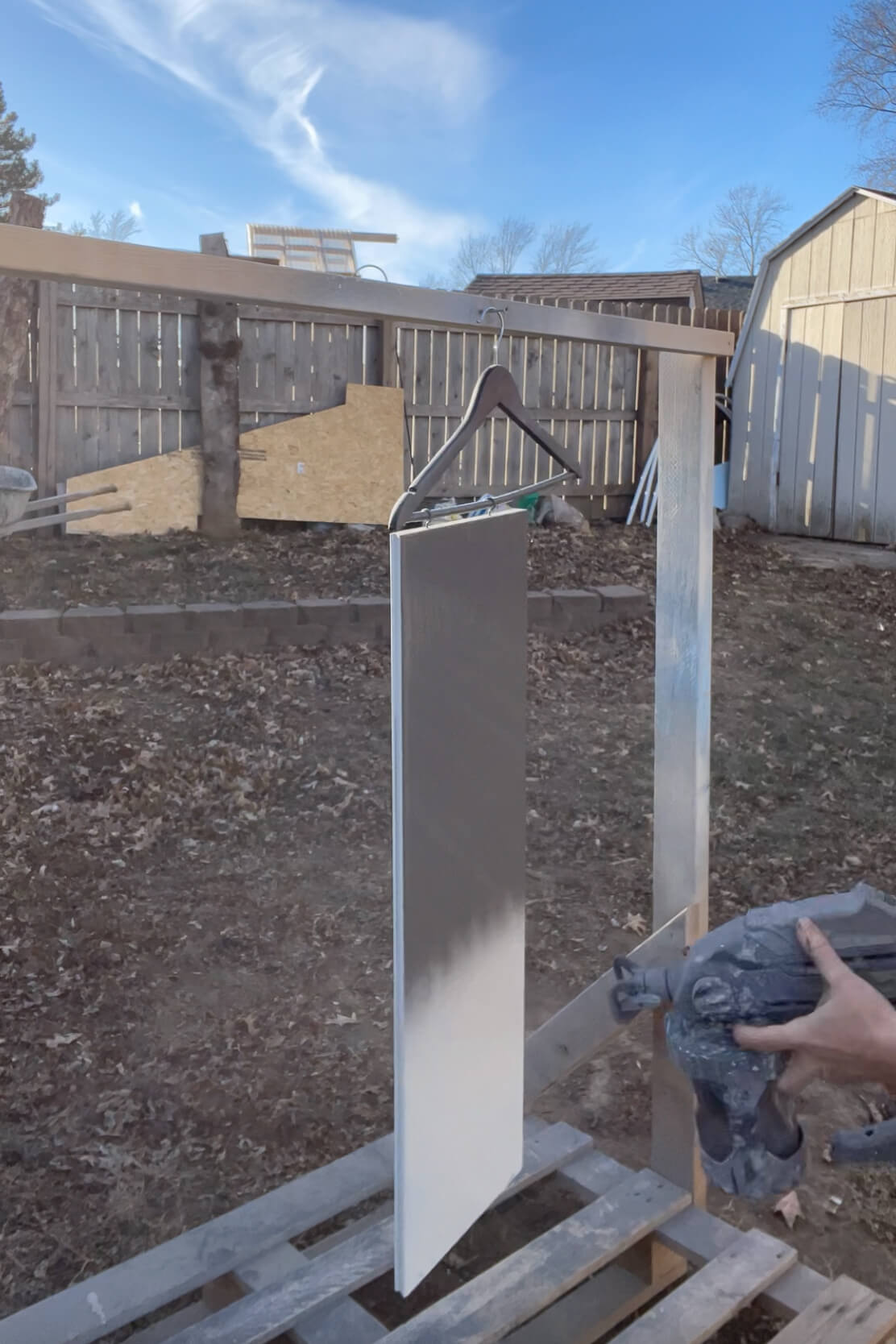 Using a paint sprayer to paint shelves.